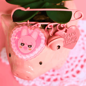 Acrylic pin of SKZOO Dwaekki with a pink bell and heart charm